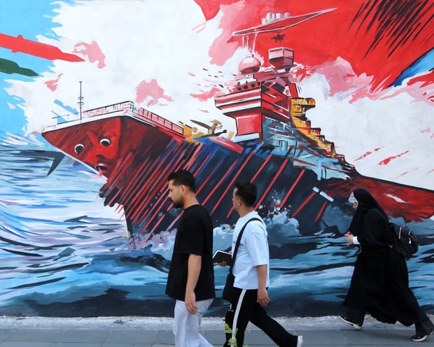 &nbsp;إيرانيون يسيرون أمام جدارية في طهران