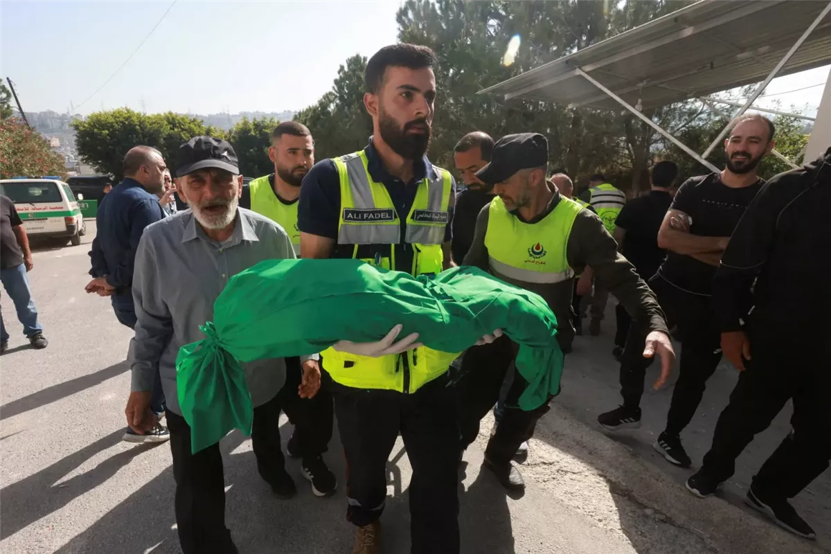 عنصر في الدفاع المدني يحمل الطفلة مريم فحص التي تبلغ 6 أشهر من عمرها والتي قتلت مع عائلتها في قصف إسرائيلي استهدف قضاء صيدا