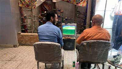 عشق الكرة.. مشجعان يشاهدان مباراة الأهلي والحرس الوطني في الشارع | صور